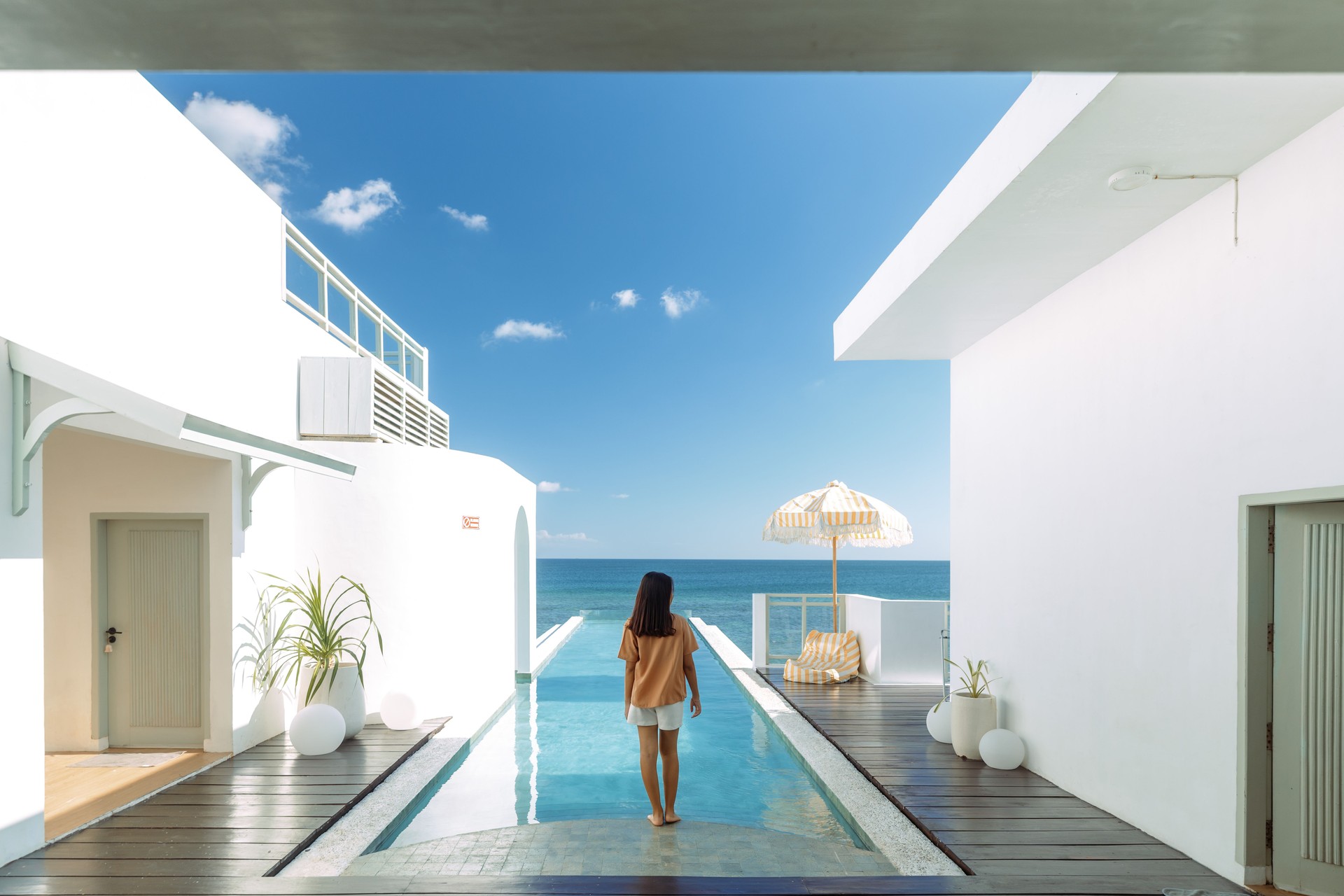 Beautiful Asian Woman Standing at the Edge of Infinity Pool in A Luxury Beach Villa
